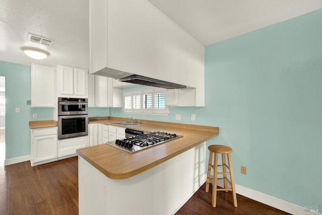 kitchen with a peninsula, appliances with stainless steel finishes, white cabinets, and dark wood finished floors