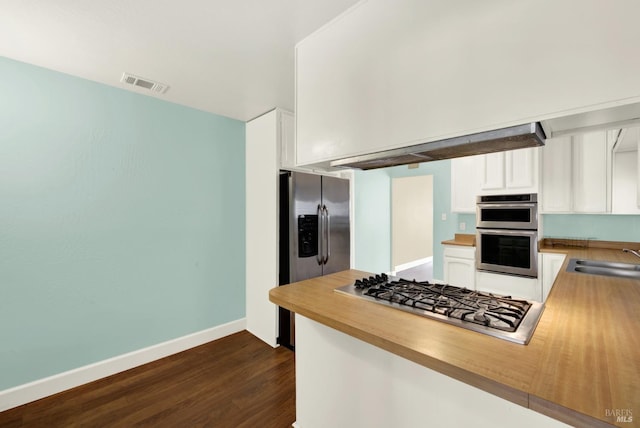 kitchen featuring stainless steel appliances, a peninsula, a sink, visible vents, and white cabinets