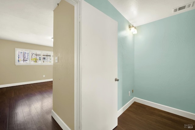 hall featuring wood finished floors, visible vents, and baseboards