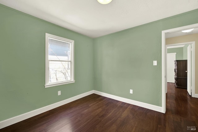 unfurnished room featuring dark wood-style flooring and baseboards