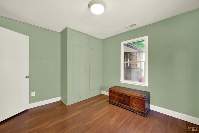 empty room featuring wood finished floors, visible vents, and baseboards