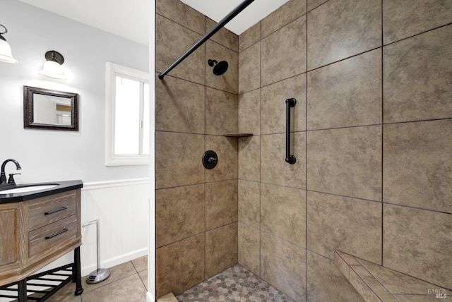 full bathroom featuring a wainscoted wall, a tile shower, vanity, and tile patterned floors