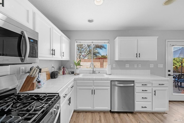 kitchen with plenty of natural light, white cabinetry, stainless steel appliances, and a sink