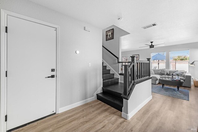 foyer with stairs, light wood-style flooring, visible vents, and ceiling fan