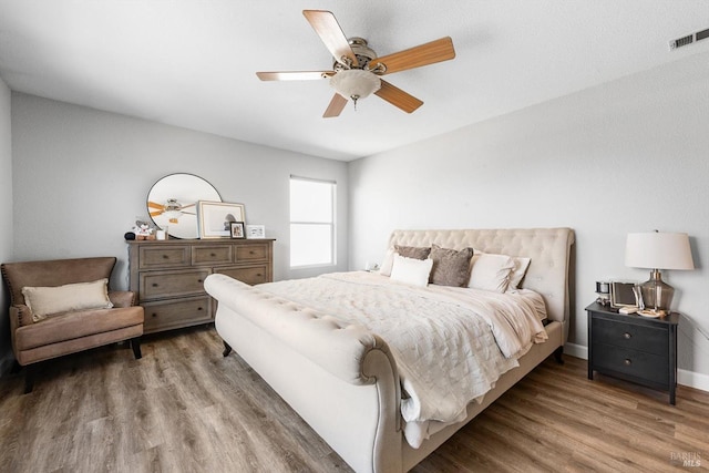 bedroom with visible vents, a ceiling fan, baseboards, and wood finished floors