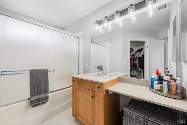 bathroom with vanity, a walk in closet, visible vents, and enclosed tub / shower combo