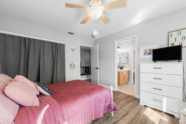 bedroom featuring visible vents, ensuite bathroom, a ceiling fan, light wood-style floors, and baseboards