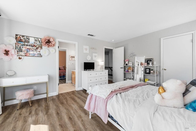 bedroom featuring visible vents, baseboards, and wood finished floors