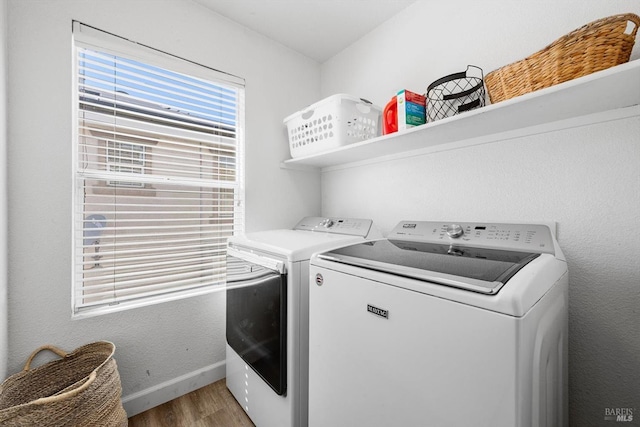 laundry area featuring light wood-type flooring, baseboards, separate washer and dryer, and laundry area