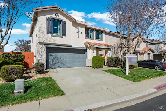 view of front of house with fence, a tile roof, concrete driveway, stucco siding, and an attached garage