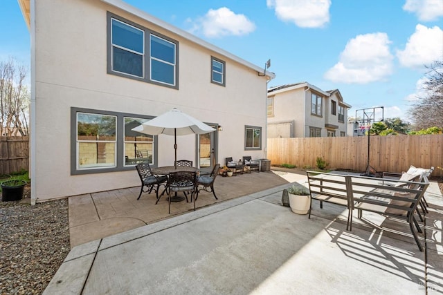 rear view of house with stucco siding, fence, outdoor dining space, and a patio area