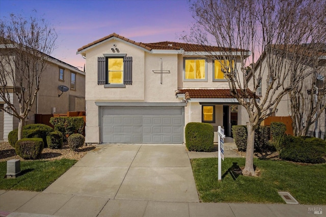 view of front facade featuring stucco siding, a tiled roof, driveway, and a garage