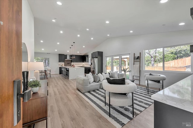 living room featuring recessed lighting, vaulted ceiling, and light wood-style flooring