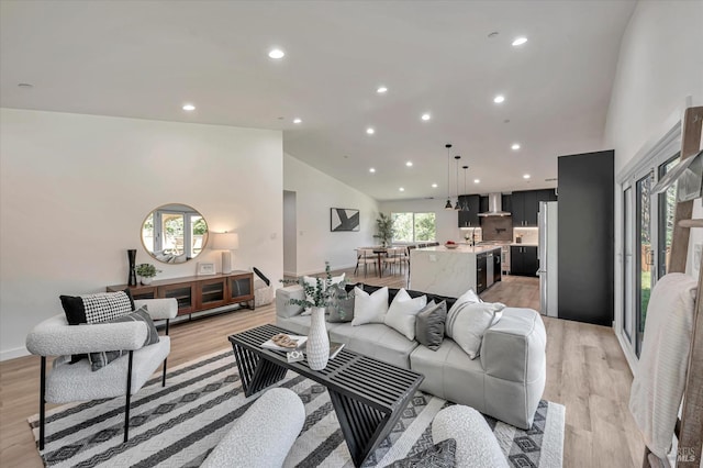 living area featuring light wood-type flooring, baseboards, high vaulted ceiling, and recessed lighting