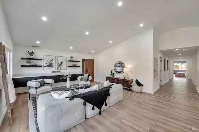 living room featuring lofted ceiling, visible vents, light wood finished floors, and recessed lighting