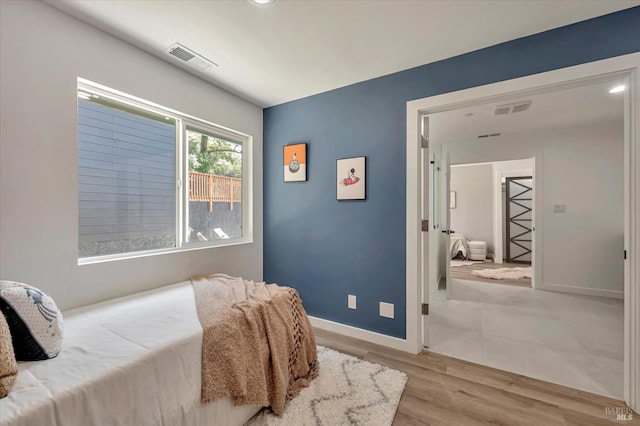 bedroom with light wood-style flooring, visible vents, and baseboards