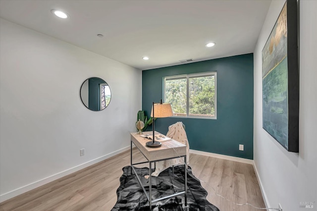 office space with light wood-type flooring, visible vents, and baseboards