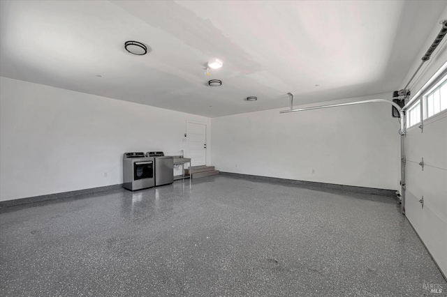 garage with baseboards and washing machine and clothes dryer