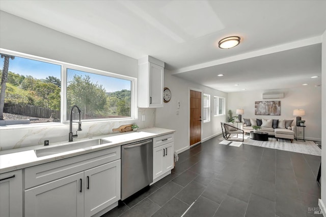 kitchen with tasteful backsplash, a wealth of natural light, stainless steel dishwasher, a wall mounted AC, and a sink