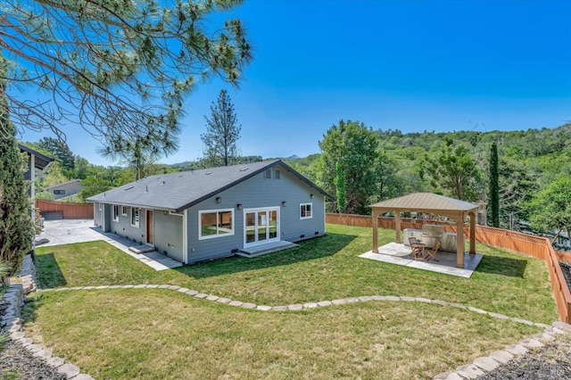 rear view of property featuring a gazebo, a lawn, a patio area, and a fenced backyard