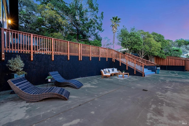 patio terrace at dusk featuring stairs and fence