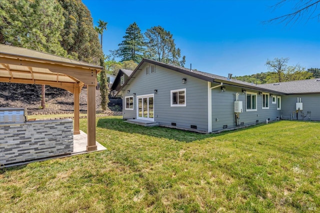 rear view of property featuring crawl space, a patio area, and a yard