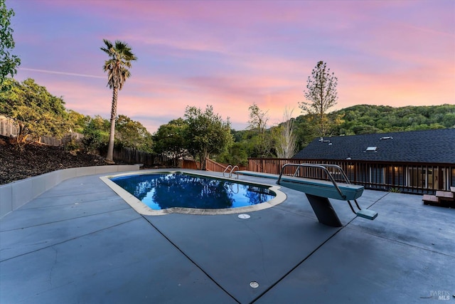 pool at dusk with a patio area, a fenced backyard, and a fenced in pool