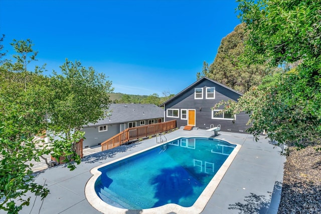 pool featuring a patio, a deck, and a diving board