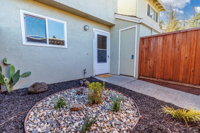 doorway to property with fence and stucco siding