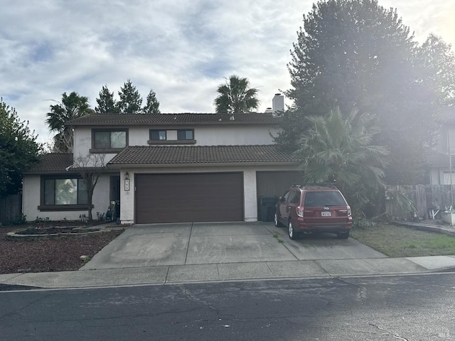 traditional home with a garage, concrete driveway, a tile roof, and stucco siding