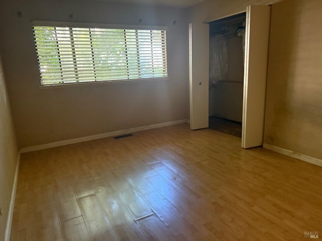unfurnished bedroom featuring baseboards, multiple windows, visible vents, and light wood-style flooring