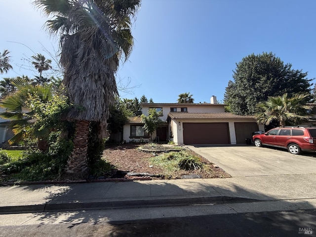 view of front of property featuring stucco siding, concrete driveway, a tiled roof, and a garage