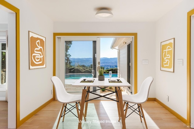 dining area featuring light wood finished floors, baseboards, and a mountain view