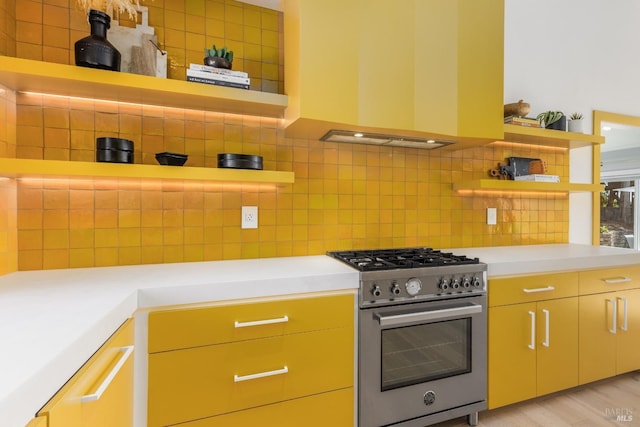 kitchen featuring high end stove, light countertops, backsplash, and open shelves