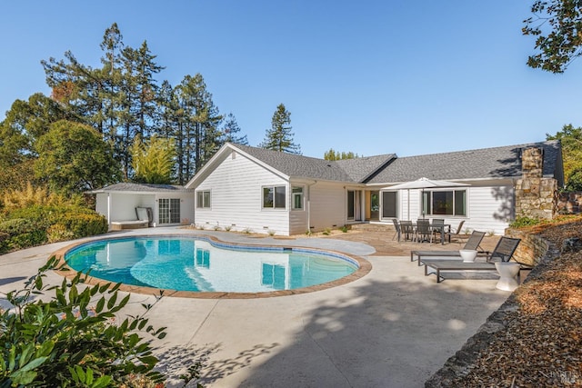 rear view of property with an outdoor pool and a patio