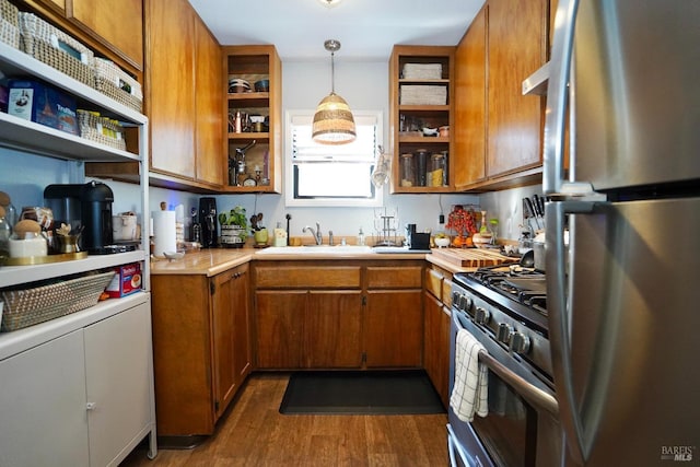 kitchen featuring brown cabinets, open shelves, light countertops, appliances with stainless steel finishes, and a sink