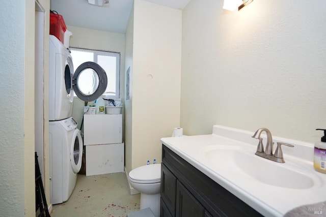 bathroom with stacked washer and dryer, concrete flooring, vanity, and toilet