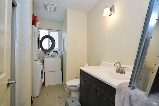 bathroom with visible vents, toilet, stacked washer / dryer, vanity, and concrete floors