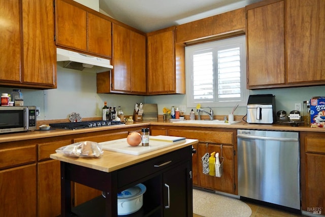 kitchen with appliances with stainless steel finishes, brown cabinets, light countertops, and under cabinet range hood