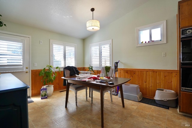 dining room featuring a wainscoted wall, lofted ceiling, and wooden walls