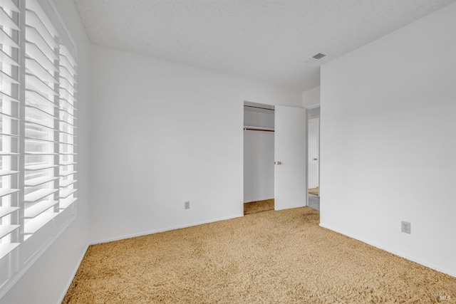 unfurnished bedroom with baseboards, visible vents, a textured ceiling, and carpet