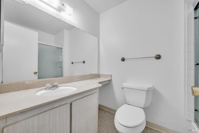 bathroom featuring baseboards, toilet, tile patterned floors, an enclosed shower, and vanity