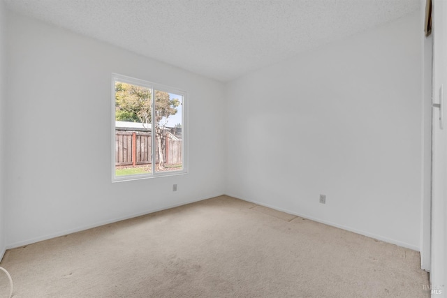 carpeted empty room with a textured ceiling and baseboards