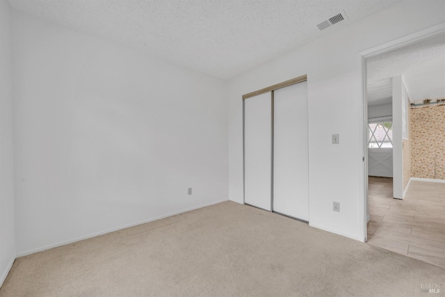 unfurnished bedroom with visible vents, baseboards, carpet flooring, a closet, and a textured ceiling