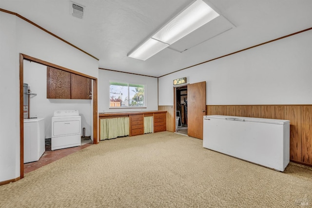 interior space with a wainscoted wall, carpet, visible vents, and washer and clothes dryer