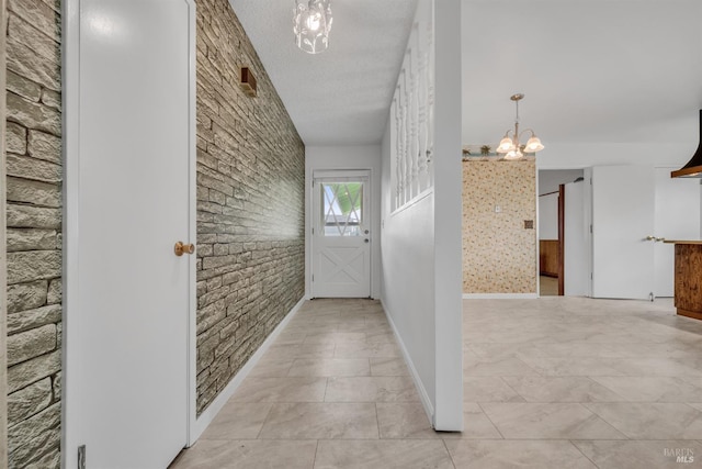 hallway with a textured ceiling and an inviting chandelier