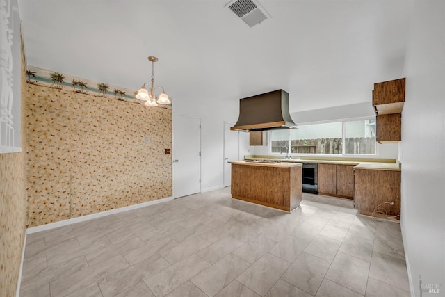 kitchen featuring visible vents, wall chimney range hood, wine cooler, brown cabinets, and a sink