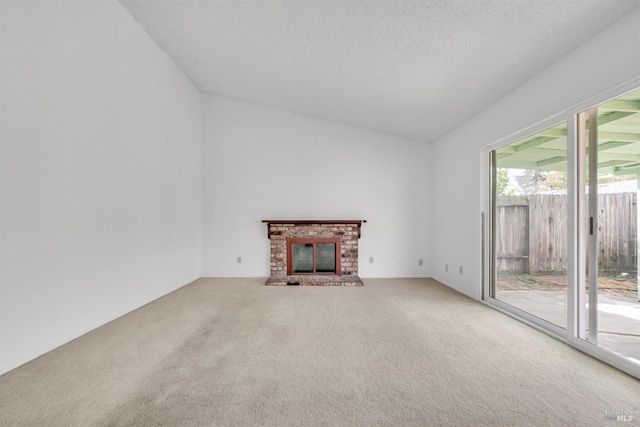 unfurnished living room featuring lofted ceiling, a brick fireplace, carpet floors, and a textured ceiling