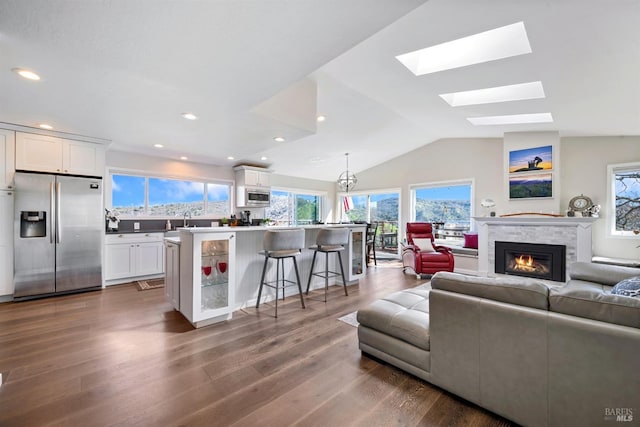 living room with lofted ceiling, recessed lighting, dark wood-style flooring, and a glass covered fireplace