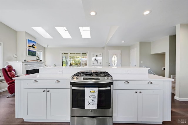 kitchen featuring dark wood-type flooring, vaulted ceiling, light countertops, open floor plan, and stainless steel range with gas cooktop